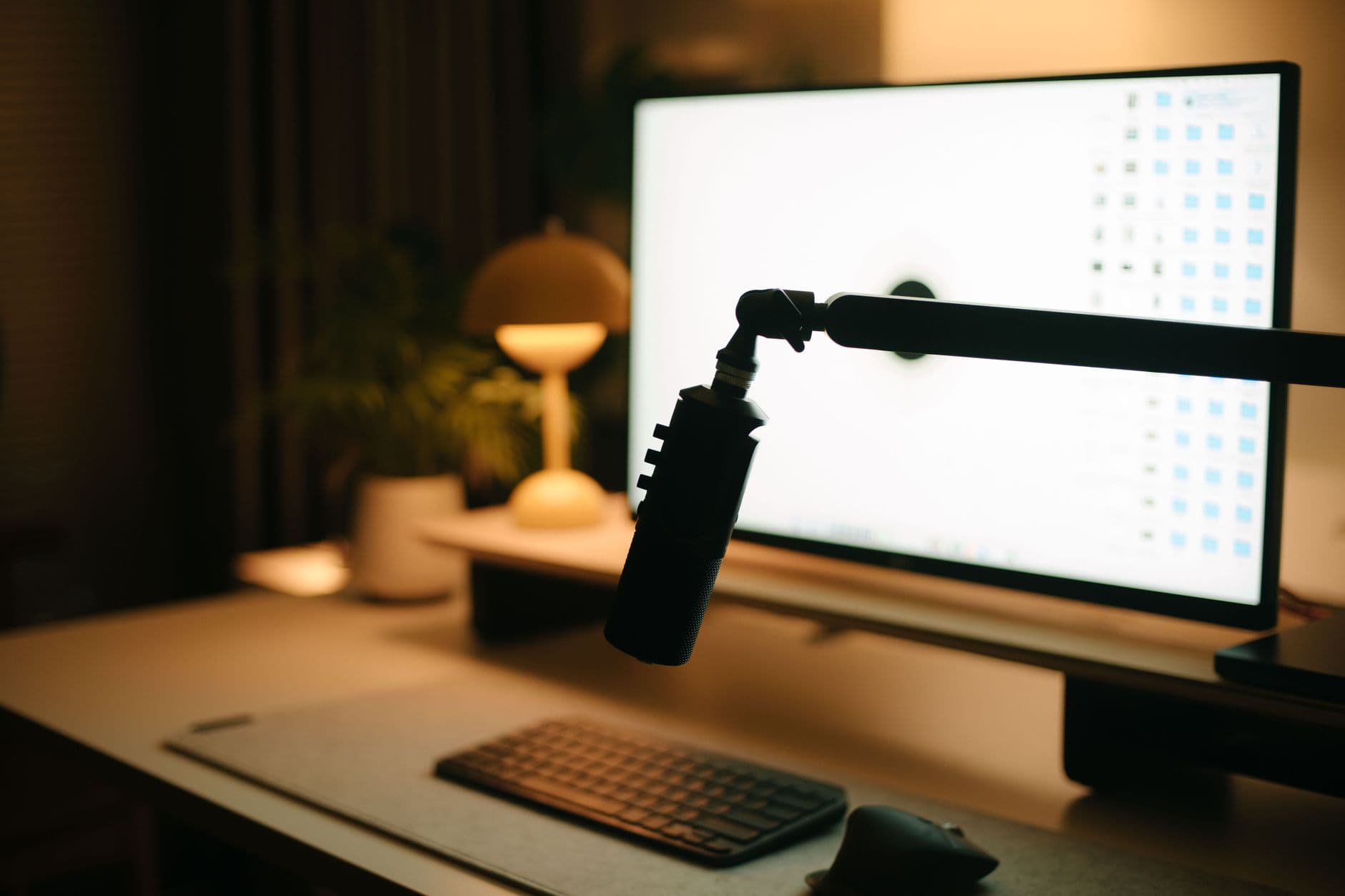 Faceless YouTube creator's desk with monitor displaying video editing software and microphone.