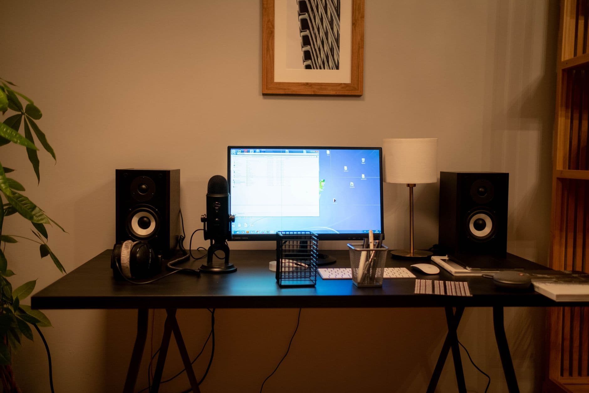 Faceless YouTube creator's desk with computer, microphone, and speakers for video production workflow.