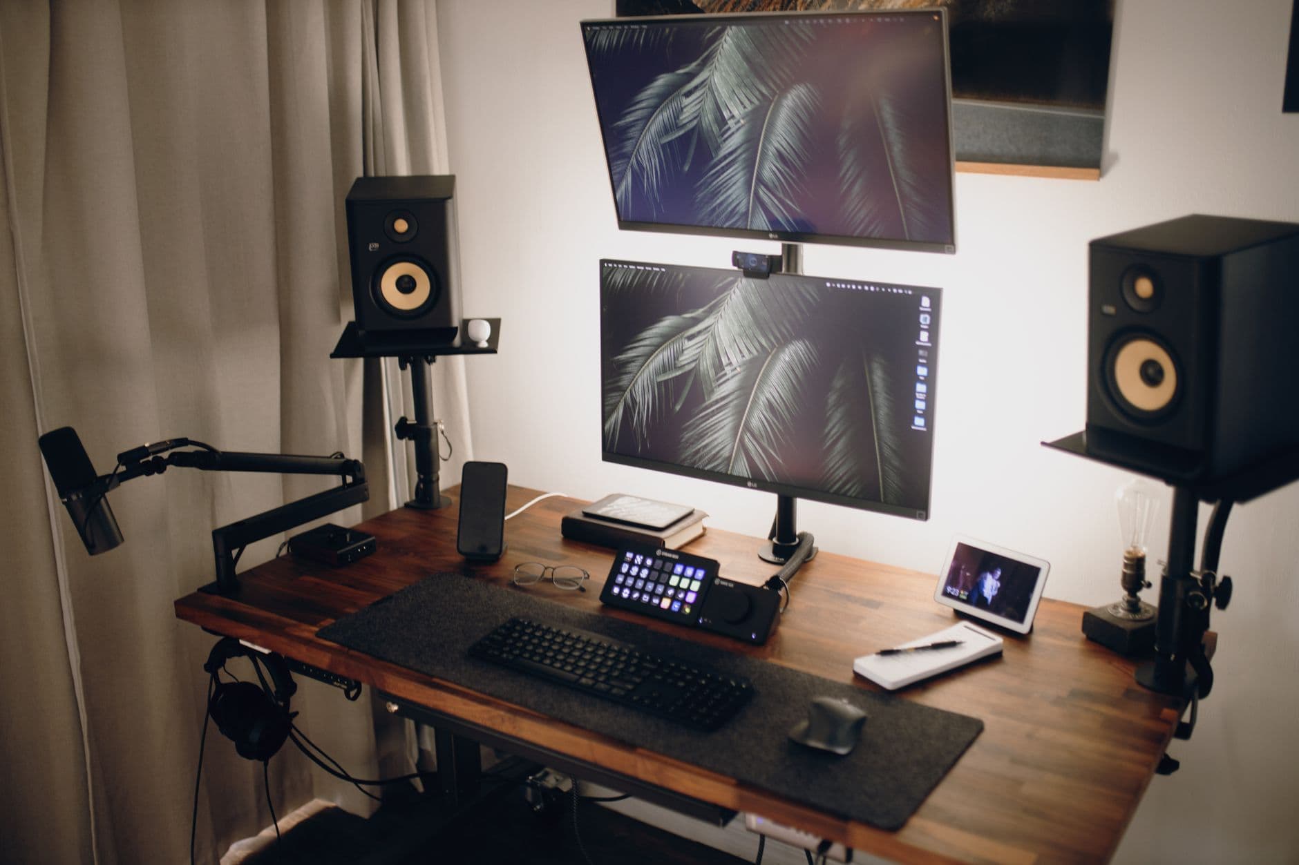 Faceless YouTube creator's dual monitor setup with audio equipment and planning tools.