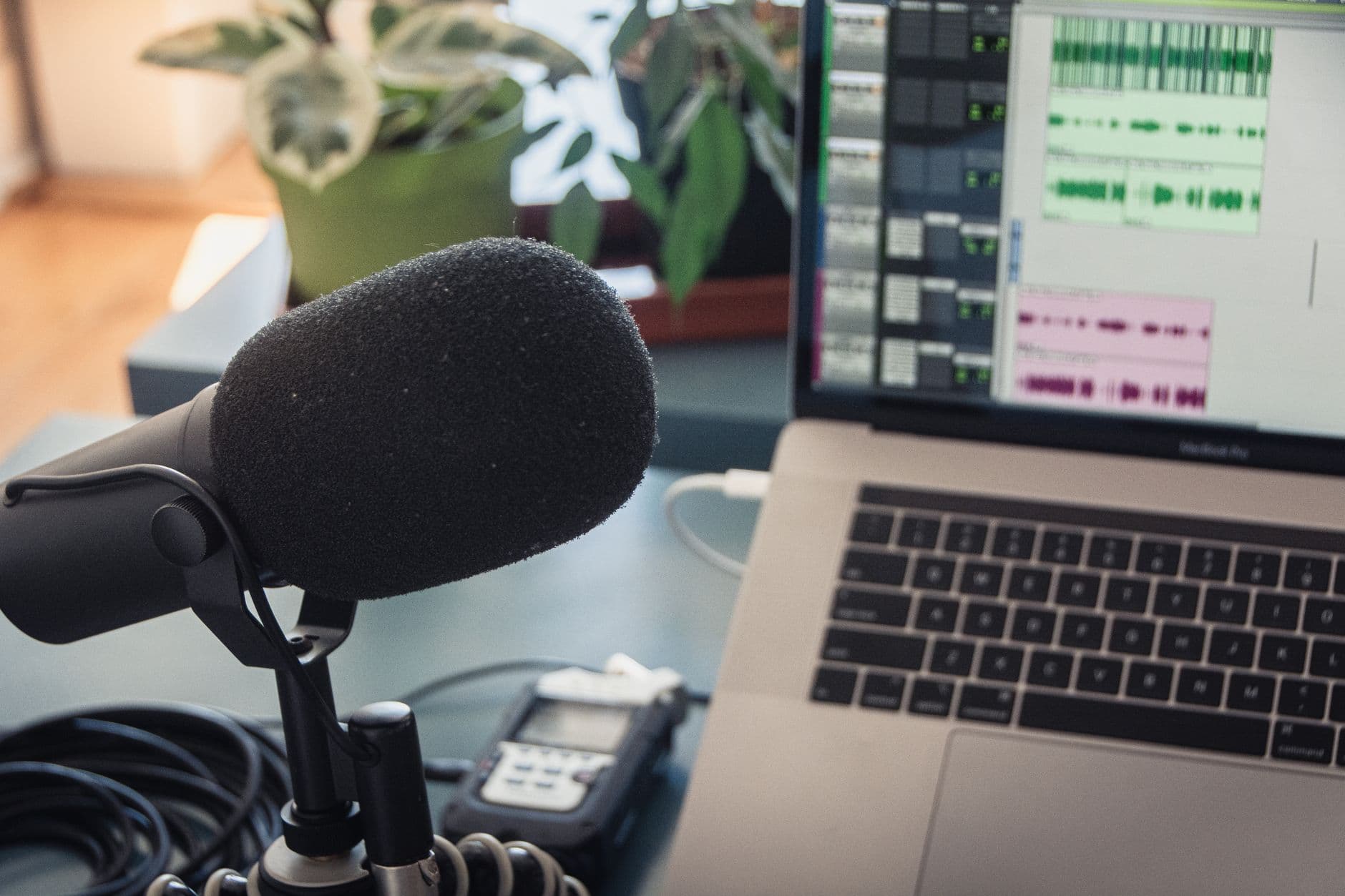 Faceless YouTube creator's microphone and laptop showing video editing timeline for on-screen text and graphics.