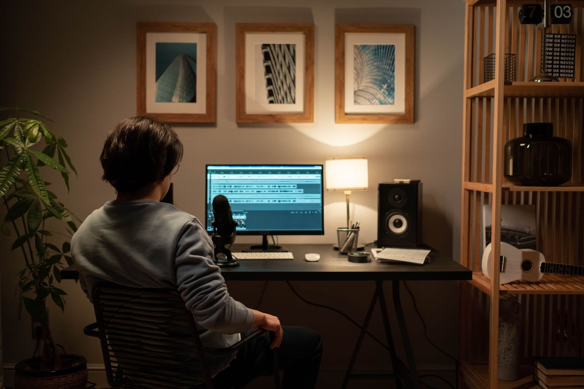 Faceless YouTube creator's workspace with editing software on monitor and microphone.