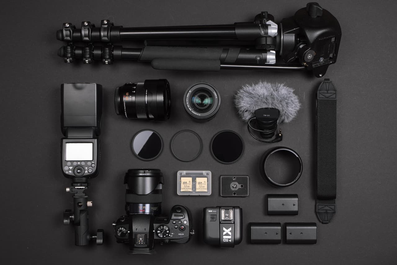 Flat lay of camera gear including a DSLR, lenses, flash, and accessories for content creation.