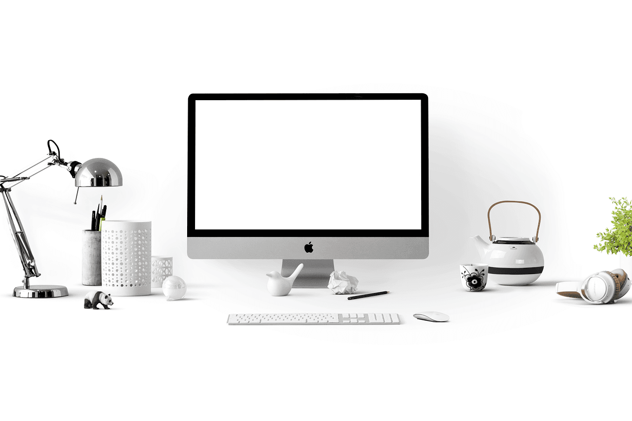 Clean desk with Apple iMac, keyboard, and headphones for faceless YouTube content creation.