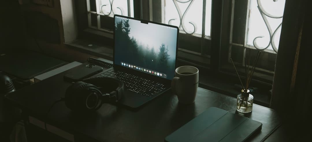 Faceless YouTube creator's desk with laptop, headphones, and coffee for script research.