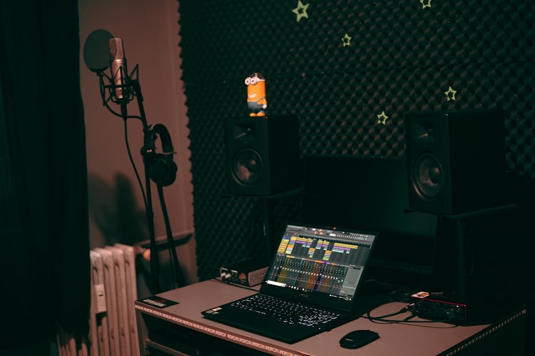 Faceless YouTube creator's studio setup with laptop showing video editing timeline and audio equipment.