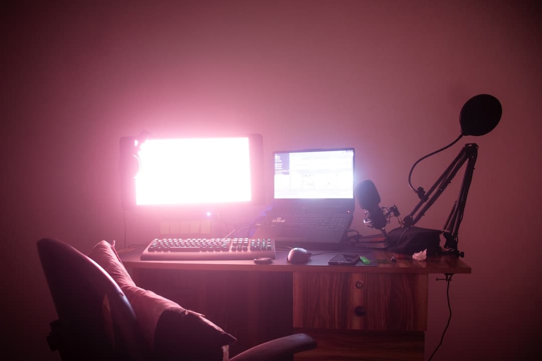 Faceless YouTube creator's desk with dual monitors and microphone setup for content strategy.