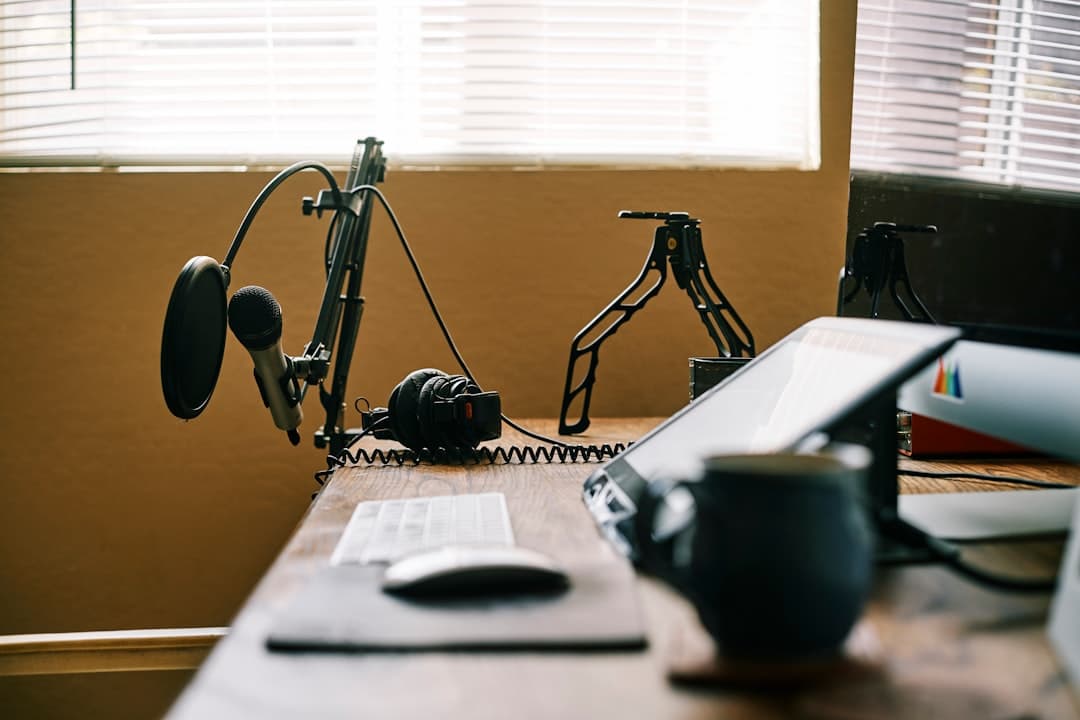 Faceless YouTube creator's desk setup with microphone, headphones, and laptop for video production.