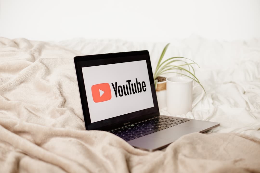 Laptop displaying YouTube interface on a blanket, suggesting a faceless creator workspace.