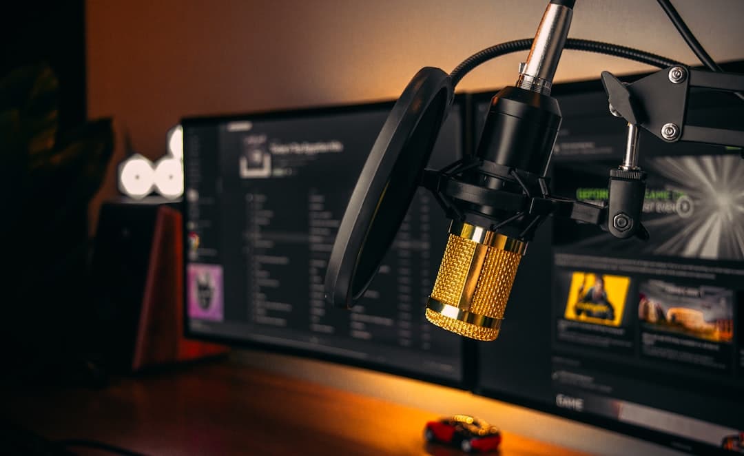 Dual monitors display YouTube content and editing software next to a gold microphone setup.