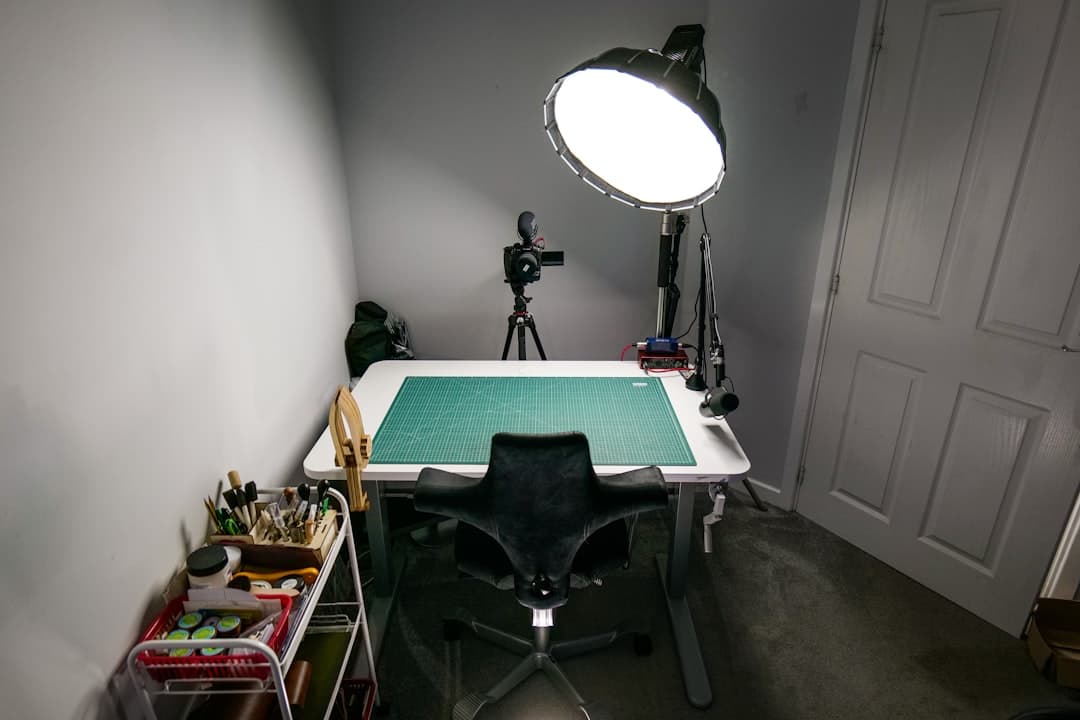 Faceless YouTube creator's empty desk with camera, microphone, and lighting setup for content creation.