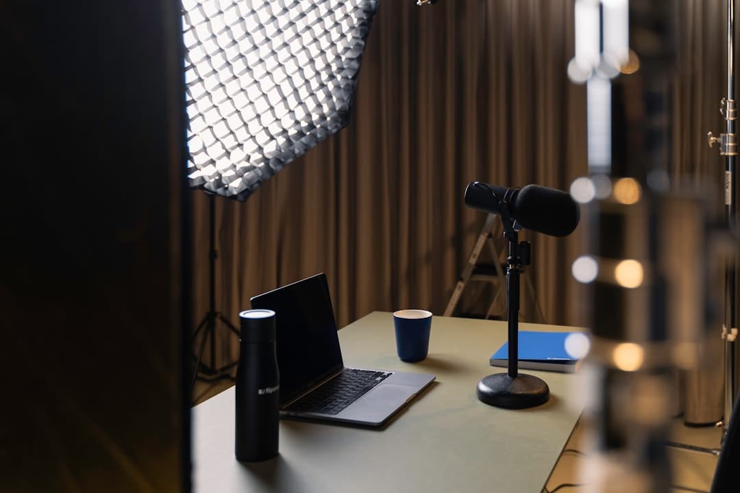 Faceless YouTube creator's desk with laptop, microphone, and lighting setup for content creation.