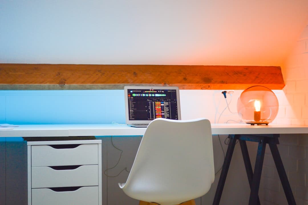 Laptop displaying video editing timeline on a desk with a lamp, for faceless YouTube channel strategy.