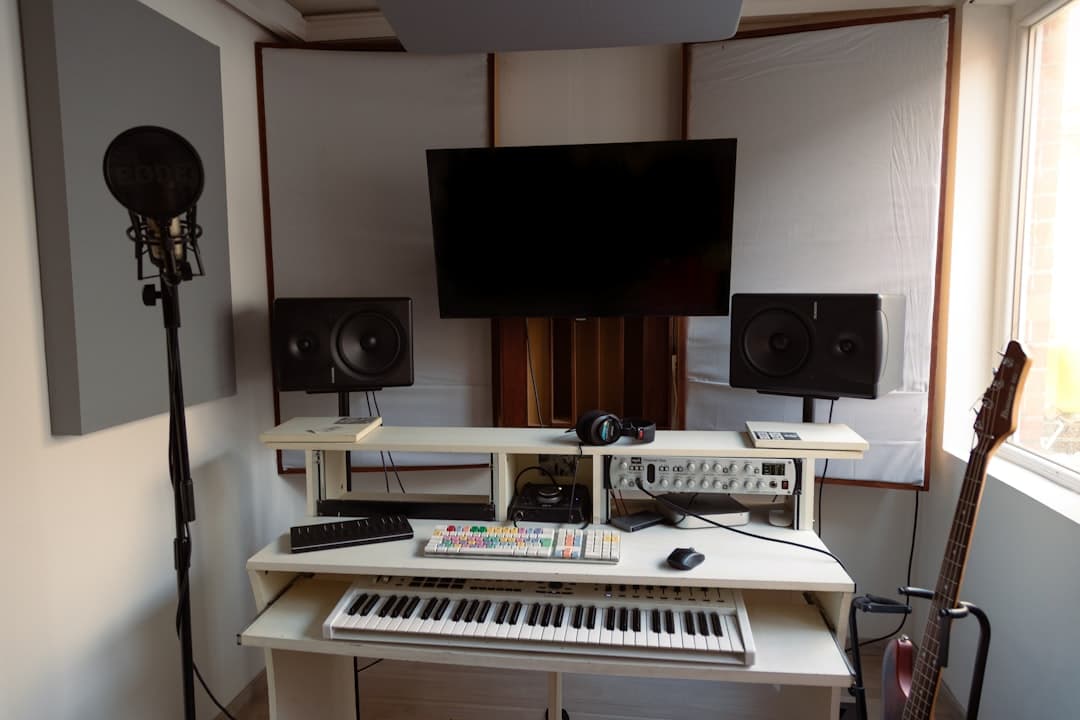 Faceless YouTube creator's studio desk with keyboard, monitors, and audio equipment for AI niche research.