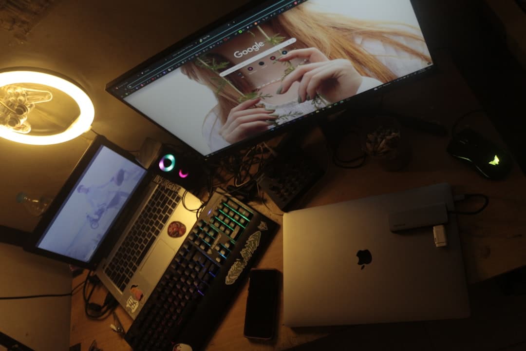 Faceless YouTube creator's desk with multiple monitors displaying video editing and analytics dashboards.