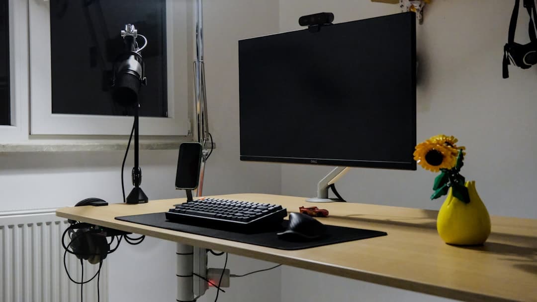 Faceless YouTube creator's desk with monitor showing audio editing software and microphone.