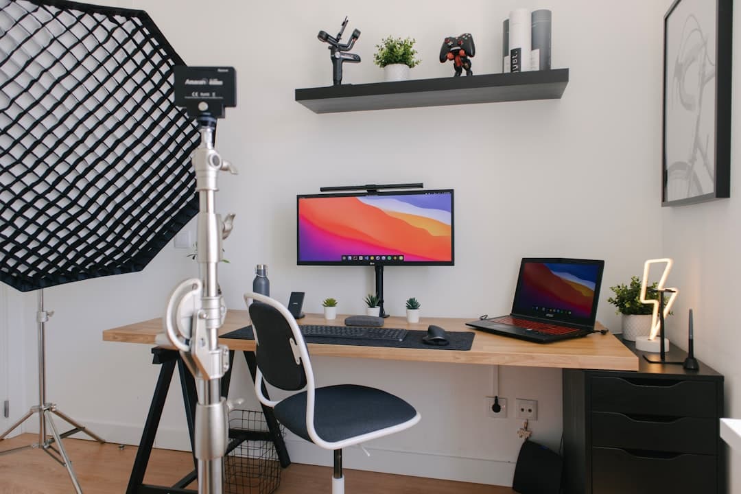 Faceless YouTube creator's desk with monitors, laptop, and recording equipment for channel growth.