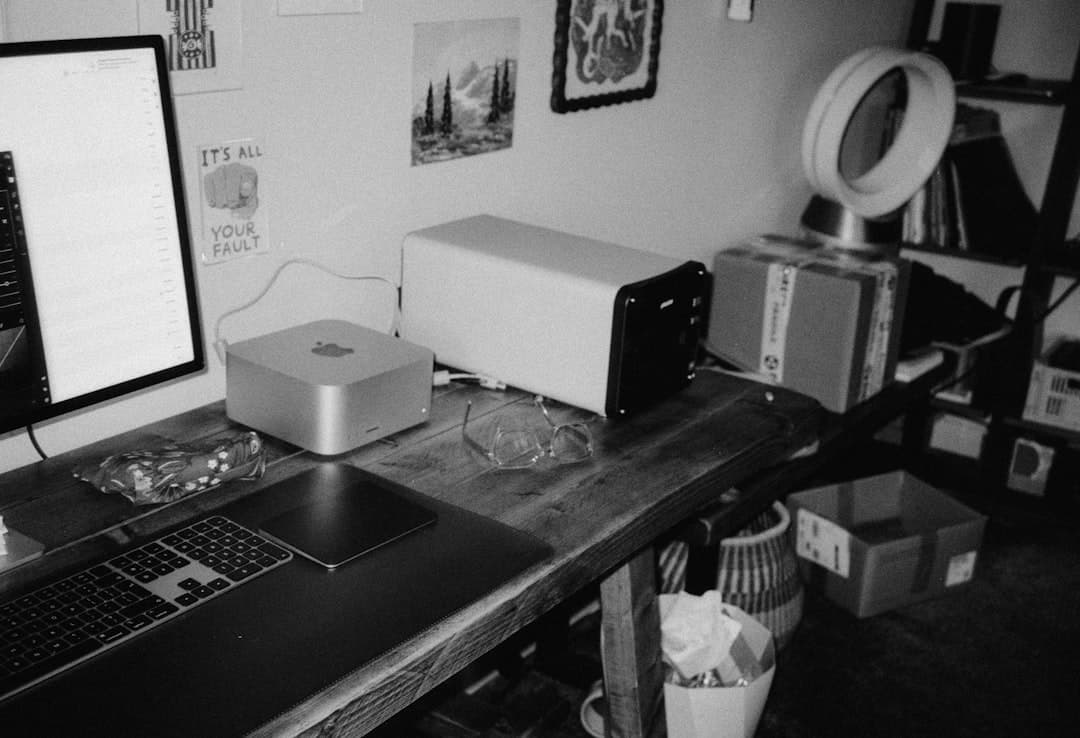 Faceless YouTube creator's desk with Mac computer, monitor, and keyboard for AI analysis and content strategy.