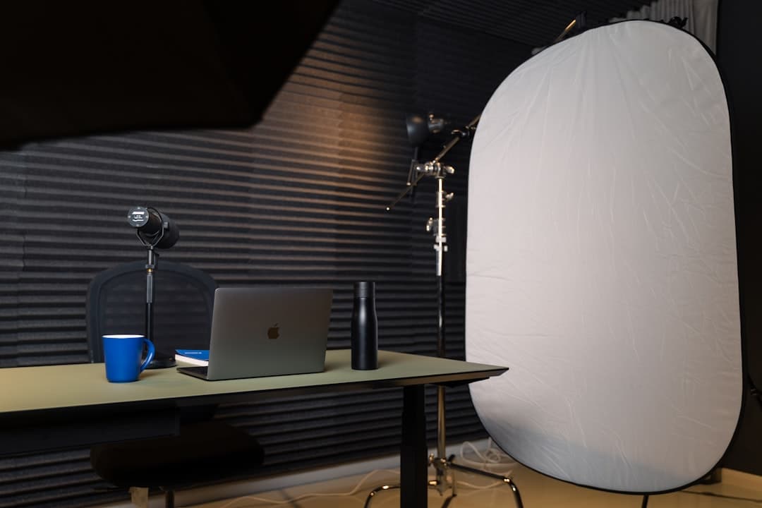 Faceless YouTube creator's desk with laptop, mug, and recording equipment for AI stack audit.
