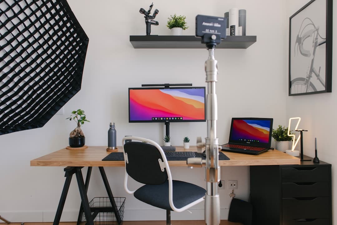 Clean desk setup with a monitor displaying a colorful desktop background and a laptop for faceless YouTube channel content creation.