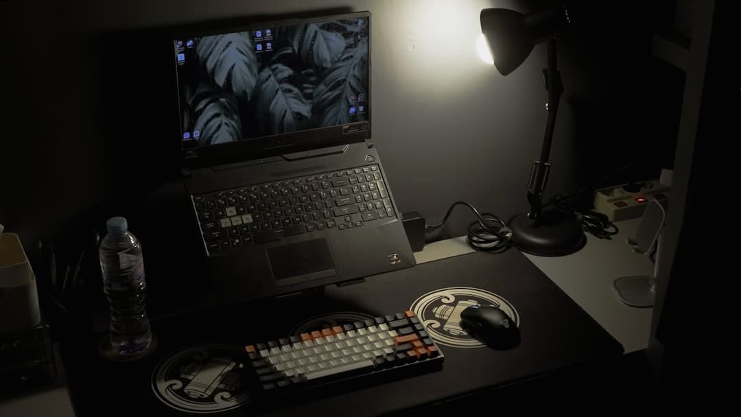 Faceless YouTube creator's desk setup with laptop and keyboard for competitor analysis.