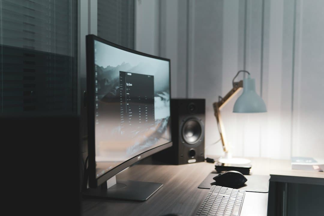 Clean desk setup with curved monitor displaying content, speaker, and lamp for faceless YouTube workflow.