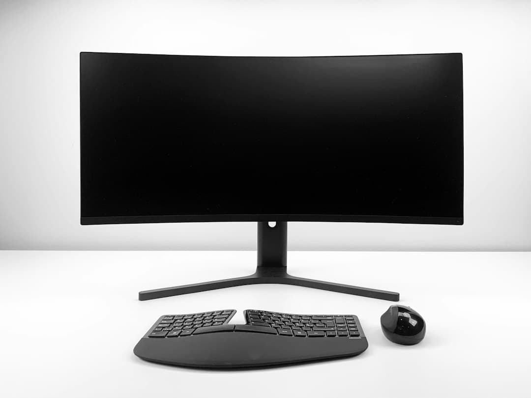 Curved monitor, ergonomic keyboard, and mouse on a clean desk for AI stack consolidation.